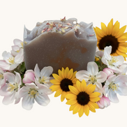 Creation Essential's Natural Body Honey Harvest soap bar topped with dried flowers, surrounded by sunflowers and blossoms