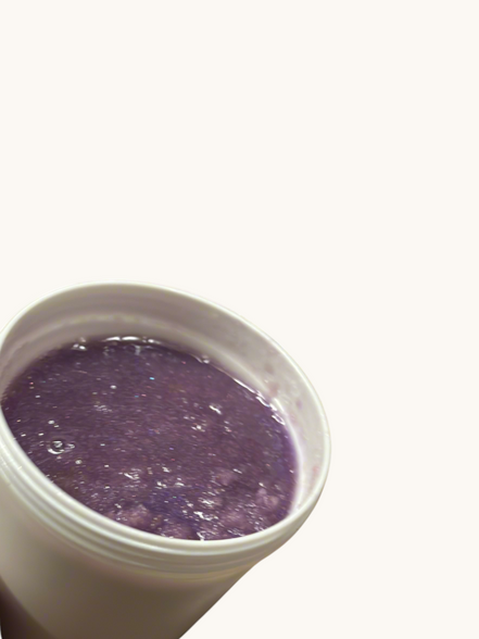 Creation Essential's Natural Body Sweet Kisses shimmer body scrub in a white jar with a purple exfoliating texture.