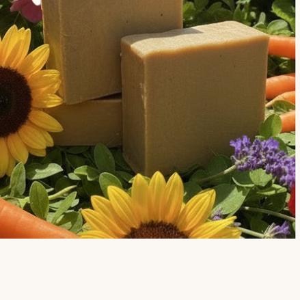 Creation Essential's Natural Body Carrot Delight bar soap nestled among fresh carrots, sunflowers, and hydrangeas.