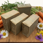 Creation Essential's Natural Body Carrot Delight bar soap with carrot oil and cucumber powder on a wooden board