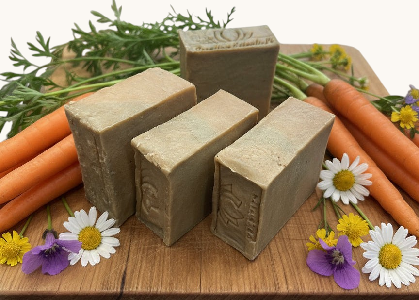 Creation Essential's Natural Body Carrot Delight bar soap with carrot oil and cucumber powder on a wooden board