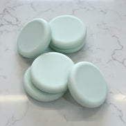 Five light green round soap bars   textured brown surface
