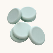 Five light green round soap bars   textured brown surface