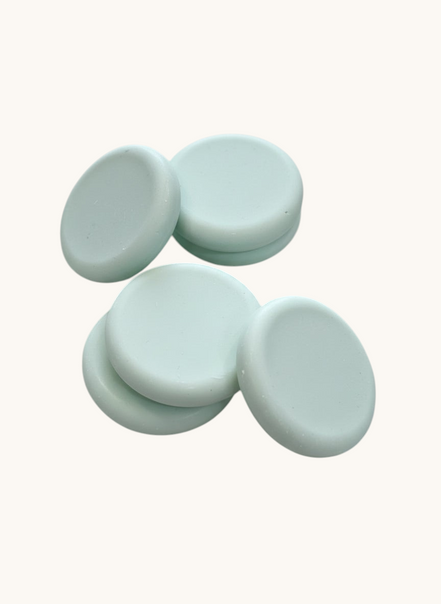 Five light green round soap bars   textured brown surface