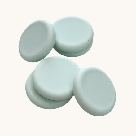 Five light green round soap bars   textured brown surface