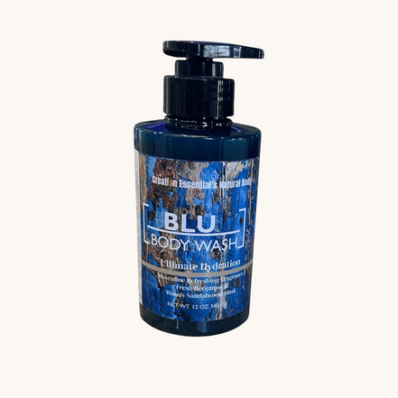 Creation Essential's Natural Body BLU organic body wash in a dark blue bottle with a pump on a wooden surface.