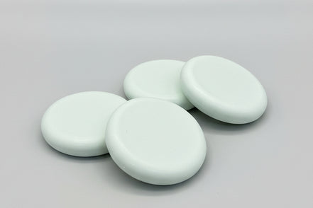 Four round soap bars  on a textured brown surface