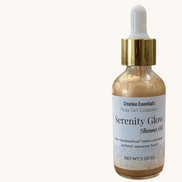 Creation Essential's Natural Body Serenity Glow shimmer oil in a glass dropper bottle with gold cap on wooden surface