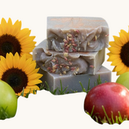 Creation Essential's Natural Body Honey Harvest soap bars topped with dried flowers, surrounded by apples and sunflowers