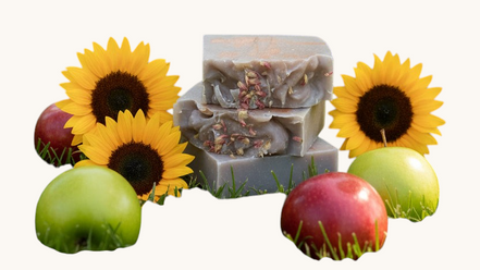 Creation Essential's Natural Body Honey Harvest soap bars topped with dried flowers, surrounded by apples and sunflowers