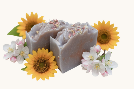 Creation Essential's Natural Body Honey Harvest soap bar topped with dried flowers, surrounded by sunflowers and apple blossoms.