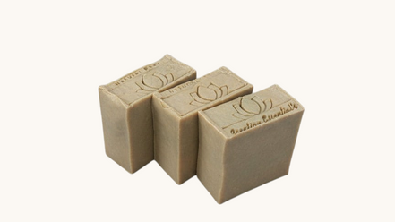 Three Creation Essential's Natural Body Carrot Delight bar soaps with a lotus flower stamp on a white background.