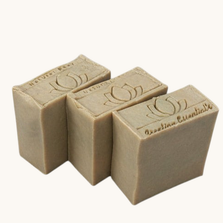 Three Creation Essential's Natural Body Carrot Delight bar soaps with a lotus flower stamp on a white background.