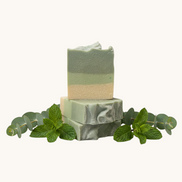 Two stacked green soap bars on a textured surface with a blurred background