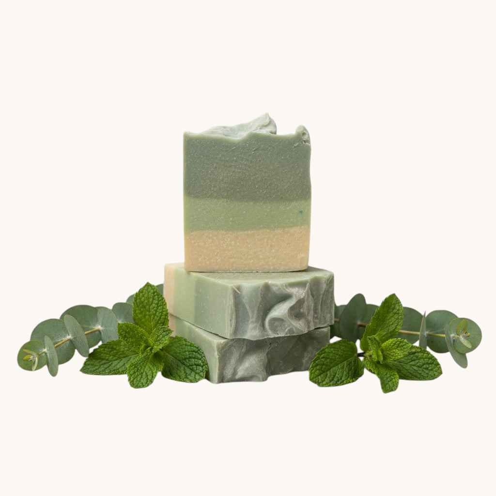Two stacked green soap bars on a textured surface with a blurred background