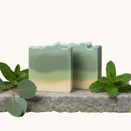 Creation Essential's Natural Body eucalyptus and spearmint bar soap on a stone slab with fresh mint and eucalyptus
