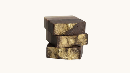 Creation Essential's Natural Body frankincense and myrrh honey bar soap with gold mica shimmer stacked on white