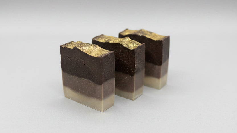 Three layered soap bars on a speckled countertop