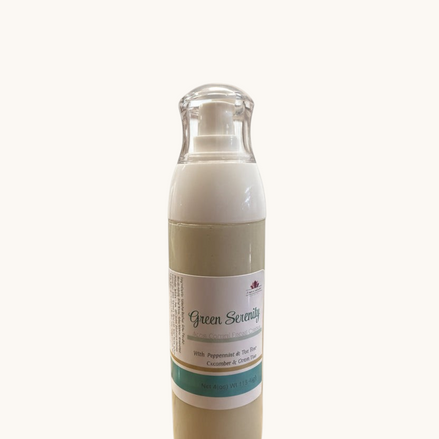 A bottle of Green Serenity facial cream with green tea and cucumber, displayed against a white brick background.