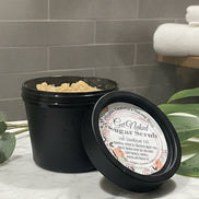 Jar of sugar scrub with a label on a reflective surface