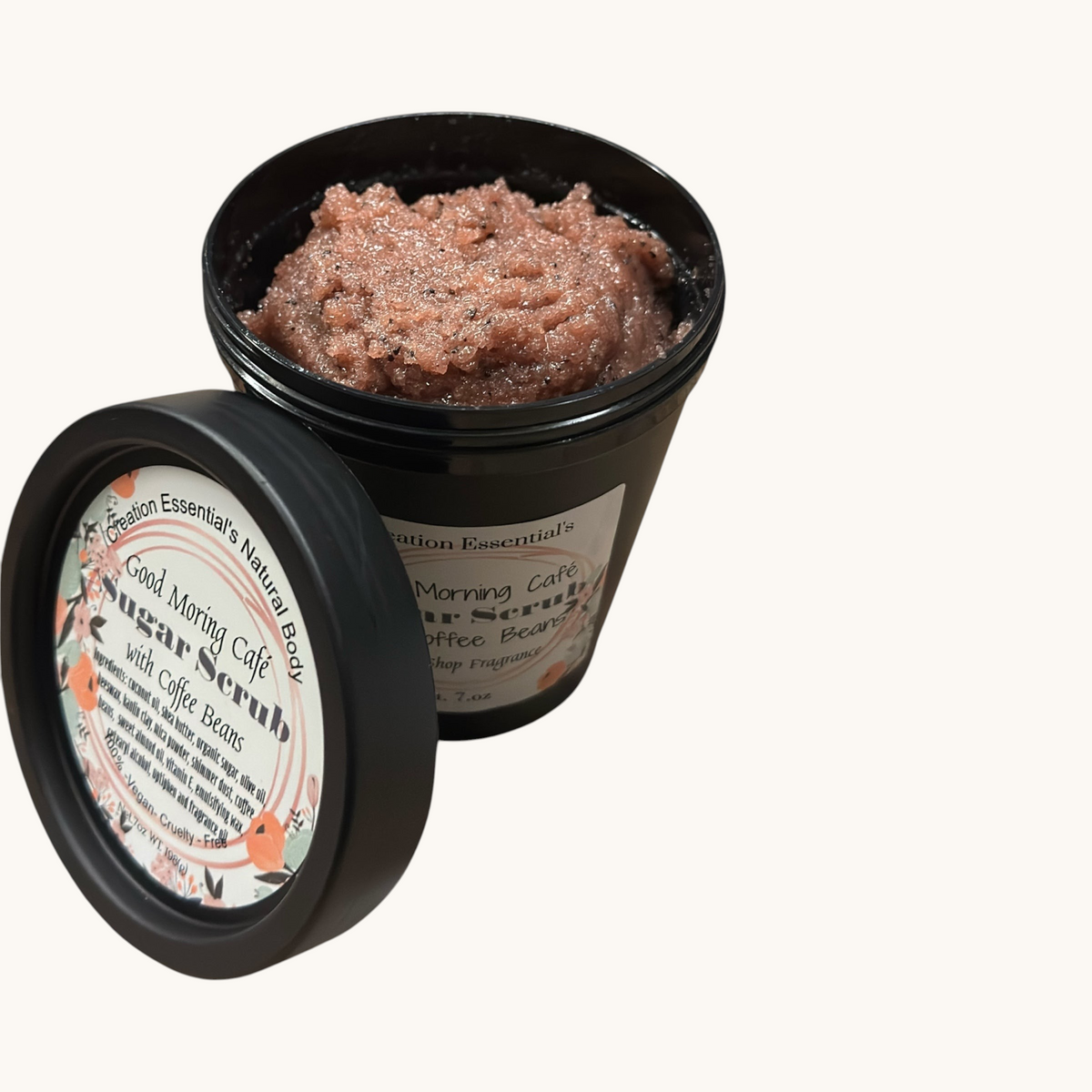 Creation Essential's Natural Body creamy coffee bean sugar scrub in a black jar on a rustic wooden surface.