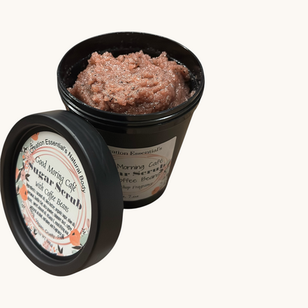 Creation Essential's Natural Body creamy coffee bean sugar scrub in a black jar on a rustic wooden surface.