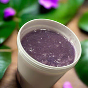 Hand holding a white container with purple Sugar Scrub 