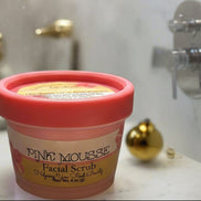 Pink mousse facial scrub container with greenery in the background