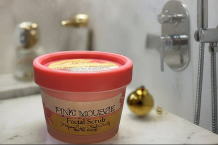 Pink mousse facial scrub container with greenery in the background