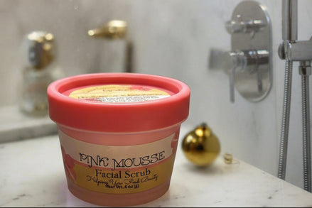 Pink mousse facial scrub container with greenery in the background