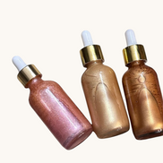 Creation Essential's Natural Body Radiant Bliss shimmer oil bundle featuring three glass dropper bottles with gold caps