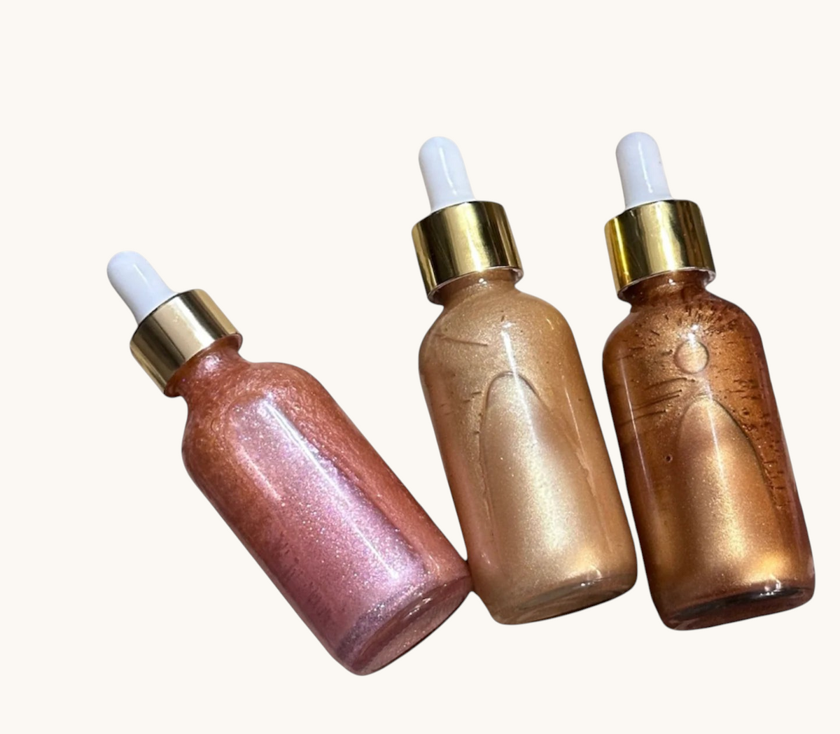 Creation Essential's Natural Body Radiant Bliss shimmer oil bundle featuring three glass dropper bottles with gold caps