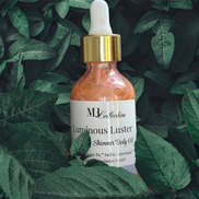 Creation Essential's Natural Body Luminous Luster shimmer body oil in a glass dropper bottle nestled in green leaves