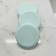 Three light green soap bars
 on a brown speckled surface