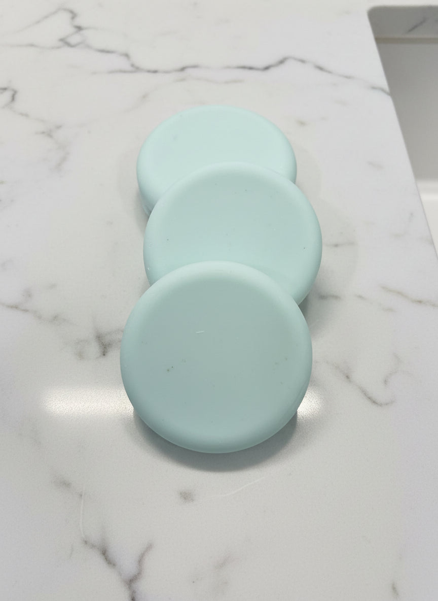 Three light green soap bars
 on a brown speckled surface