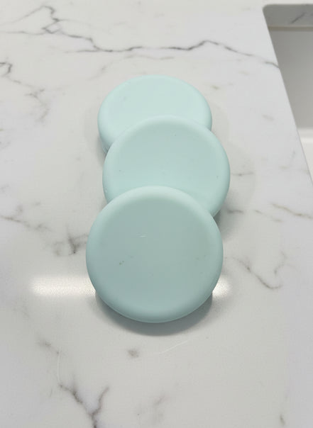 Three light green soap bars
 on a brown speckled surface