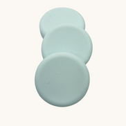 Three light green soap bars
 on a brown speckled surface