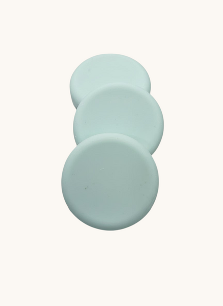 Three light green soap bars
 on a brown speckled surface