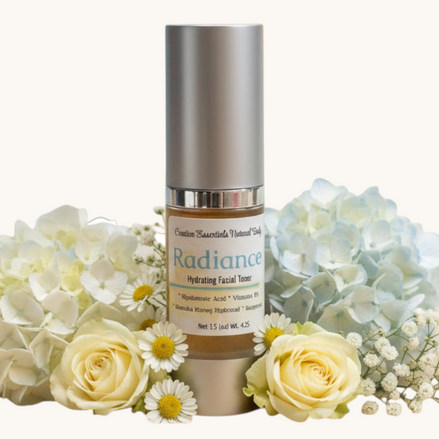 Creation Essential's Natural Body Radiance Hyaluronic Facial Toner bottle surrounded by white hydrangeas and roses.