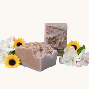 Creation Essential's Natural Body Honey Harvest soap bars topped with dried flowers, surrounded by apple blossoms.