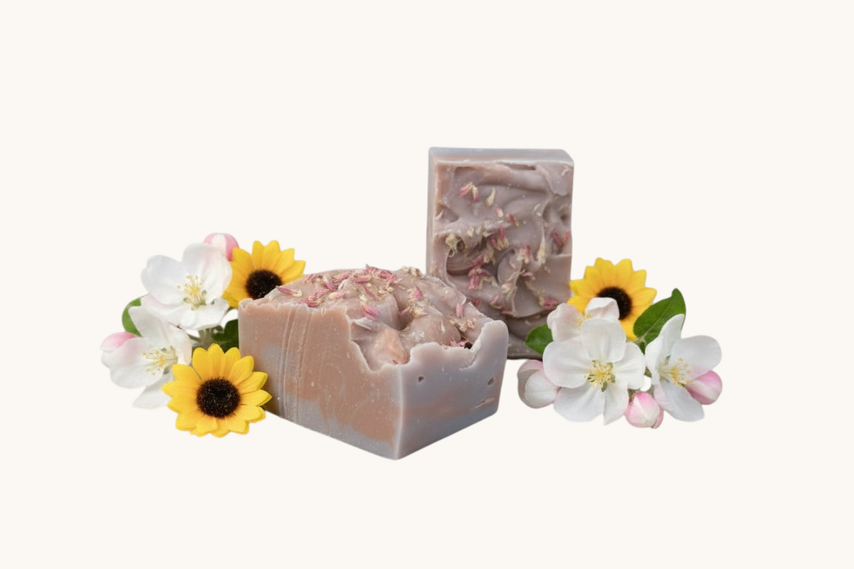Creation Essential's Natural Body Honey Harvest soap bars topped with dried flowers, surrounded by apple blossoms.
