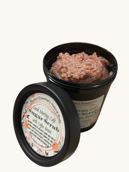 Creation Essential's Natural Body creamy coffee bean sugar scrub in a black jar with coffee beans on a marble surface.