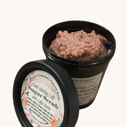 Creation Essential's Natural Body creamy coffee bean sugar scrub in a black jar with coffee beans on a marble surface.