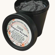 Creation Essential's Natural Body detox charcoal and pink salt shimmer sugar scrub in a black jar with floral label.