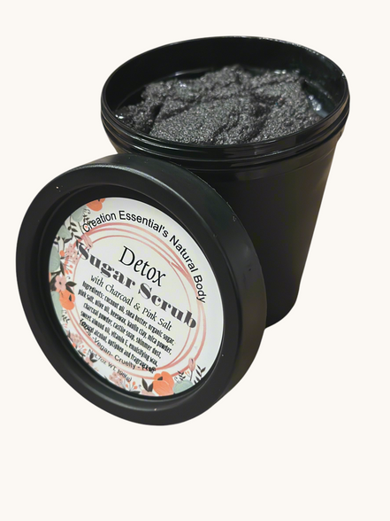 Creation Essential's Natural Body detox charcoal and pink salt shimmer sugar scrub in a black jar with floral label.