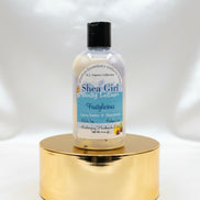 Bottle of Shea Girl body lotion on a wooden surface with a blurred background