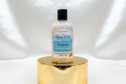 Bottle of Shea Girl body lotion on a wooden surface with a blurred background
