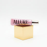 Pink lip gloss tube with gold cap on a marble surface