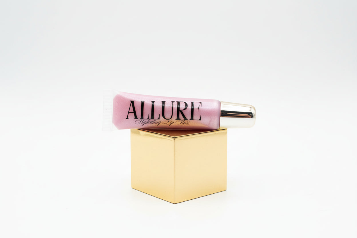 Pink lip gloss tube with gold cap on a marble surface