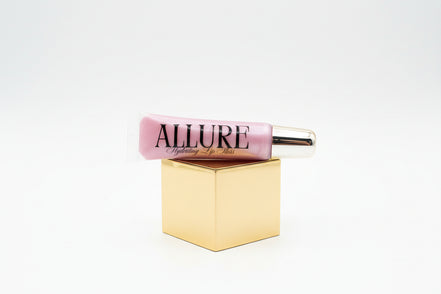 Pink lip gloss tube with gold cap on a marble surface